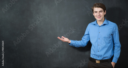 Portrait of a smart young man standing against gray background