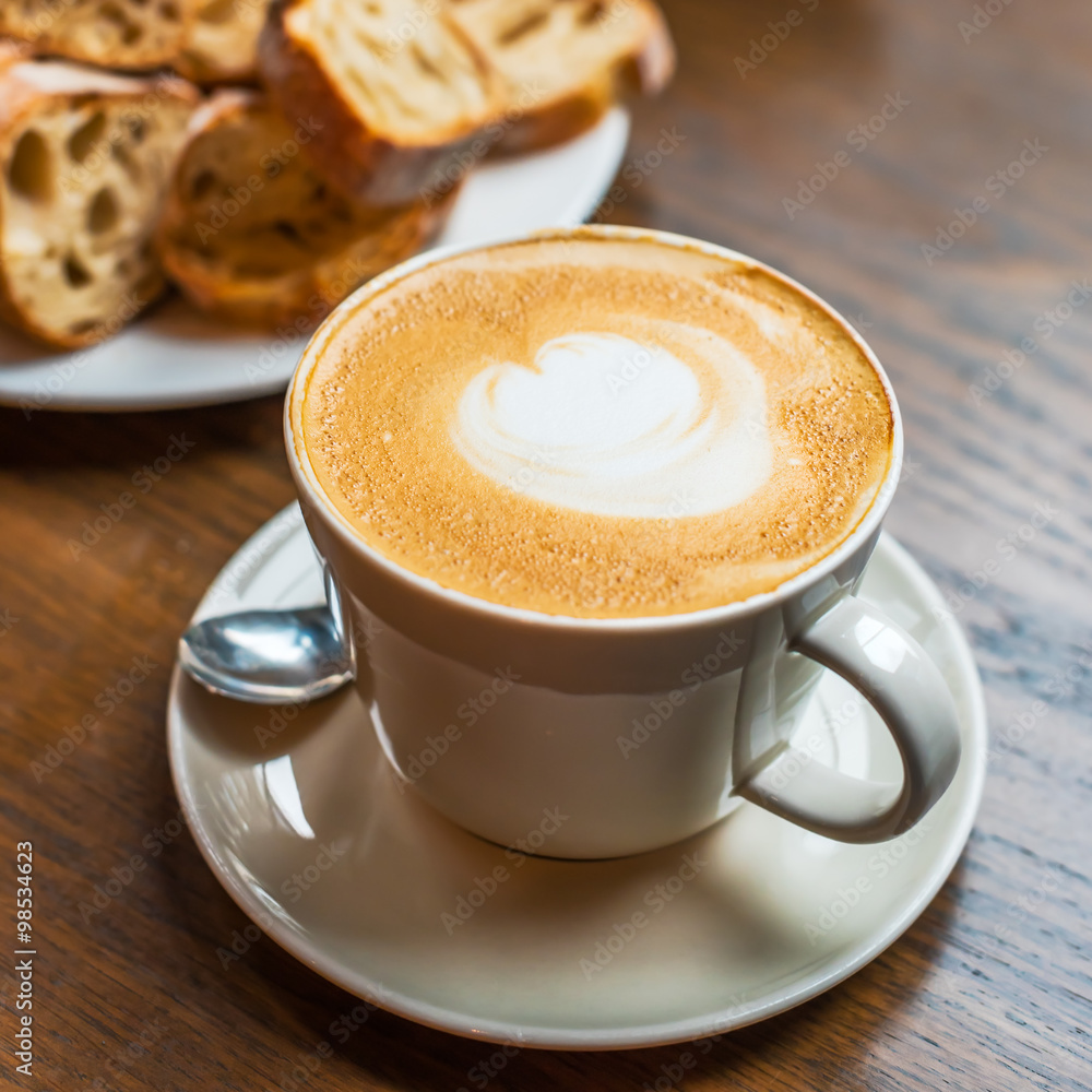 coffee cup with cream and bread on a wood table coffee cup with cream and bread on a wood table