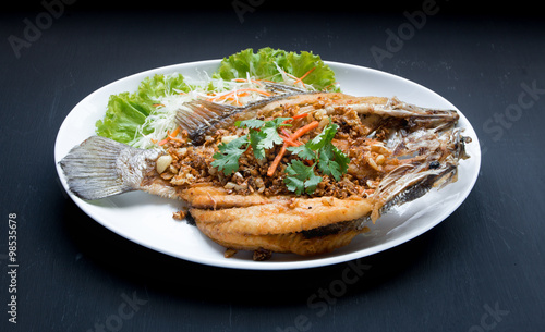 Fish dish -Deep fried Snapper fish with garlic on black backgrou