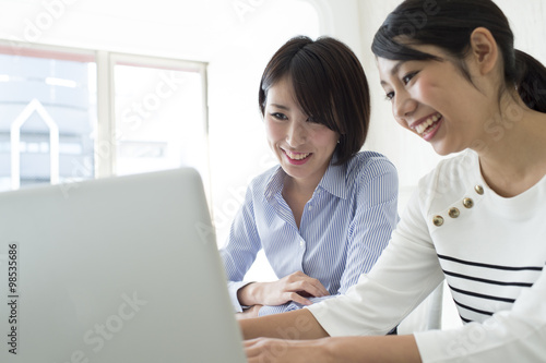 Two women are using a notebook computer in the office © Monet