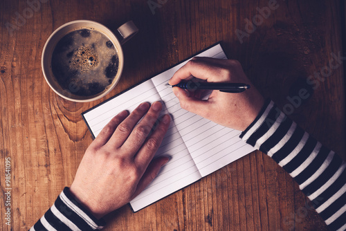 Woman drinking coffee and writing a diary note photo