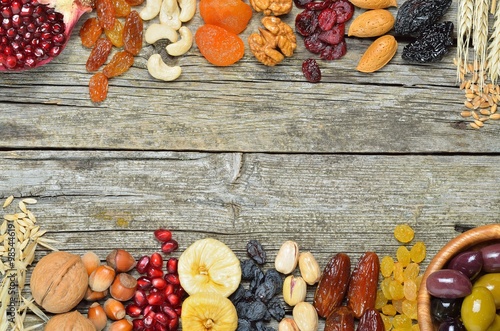 Dried fruits, barley, wheat, olives, pomegranate on a wooden table - symbols of judaic holiday Tu Bishvat .Copyspace background. Top view  photo