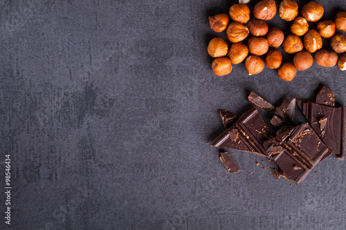 Bitter chocolate and hazelnuts on corner, black stone background.