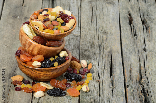 Mix of dried fruits and nuts in a wooden bowl - symbols of judaic holiday Tu Bishvat. Copyspace background.
