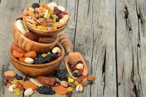 Mix of dried fruits and nuts in a wooden bowl - symbols of judaic holiday Tu Bishvat. Copyspace background.