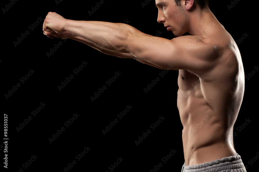 Side view of muscular young man on a black background
