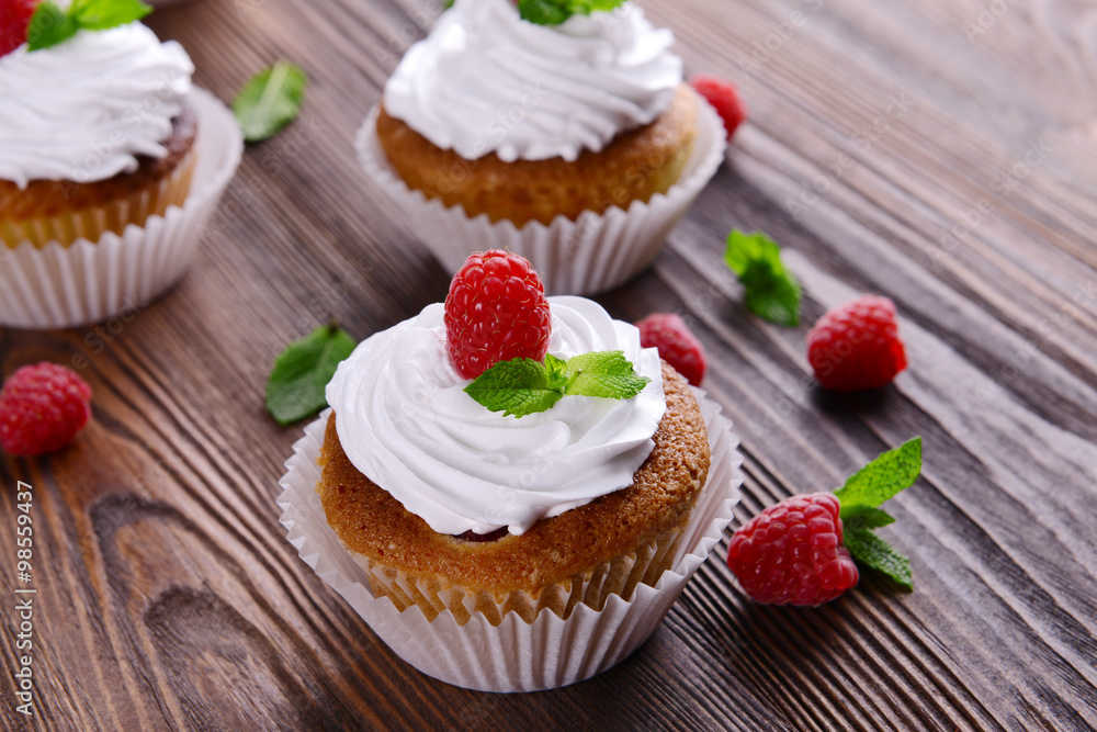 Delicious cupcakes with berries and fresh mint on wooden table close up Delicious cupcakes with berries and fresh mint on wooden table close up