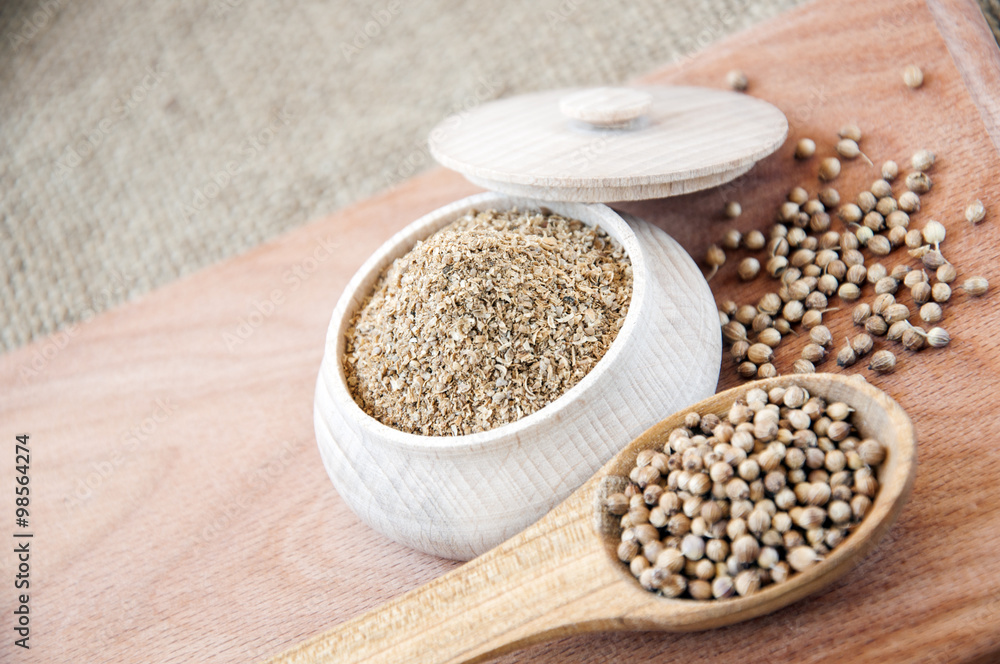 coriander seeds in a wooden spoon, milled in bowl. coriander seeds in a wooden spoon, milled in bowl.