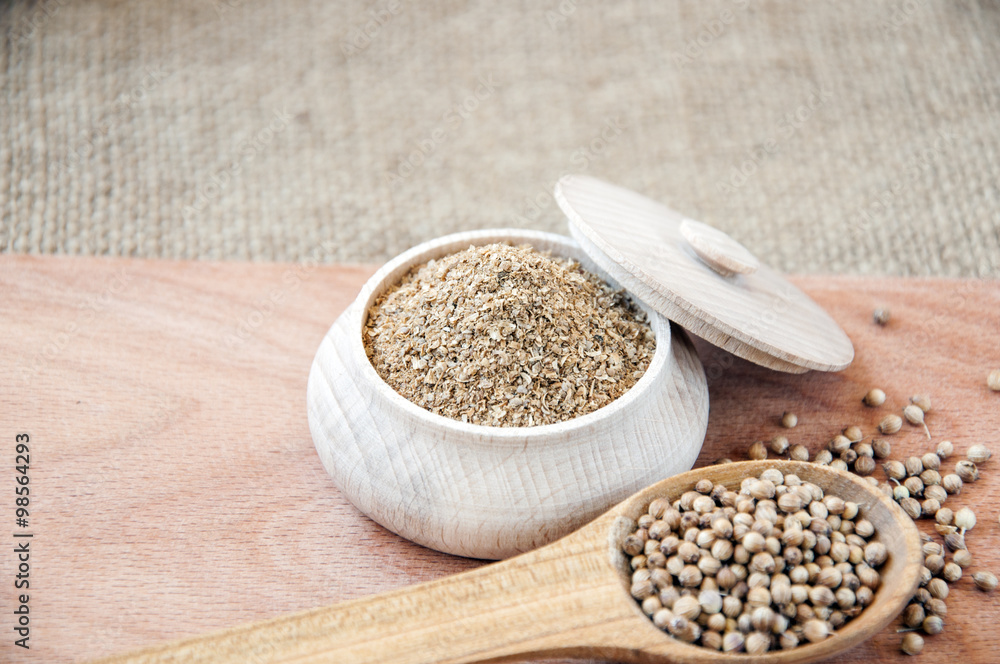 coriander seeds in a wooden spoon, milled in bowl. coriander seeds in a wooden spoon, milled in bowl.