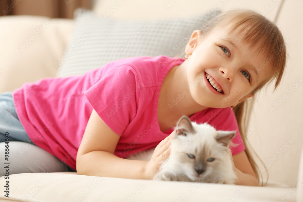 Little cute girl playing with kitten on sofa at home Little cute girl playing with kitten on sofa at home