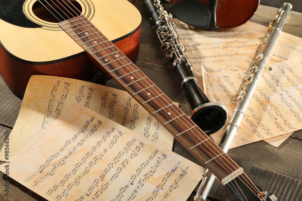 Fototapeta premium Acoustic guitar, soprano saxophone, violin, flute and note sheets on wooden background