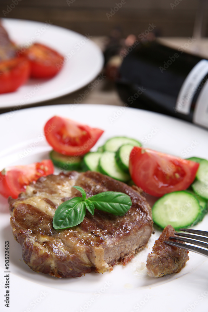 Roasted beef fillet and fresh vegetables on plate, on wooden background