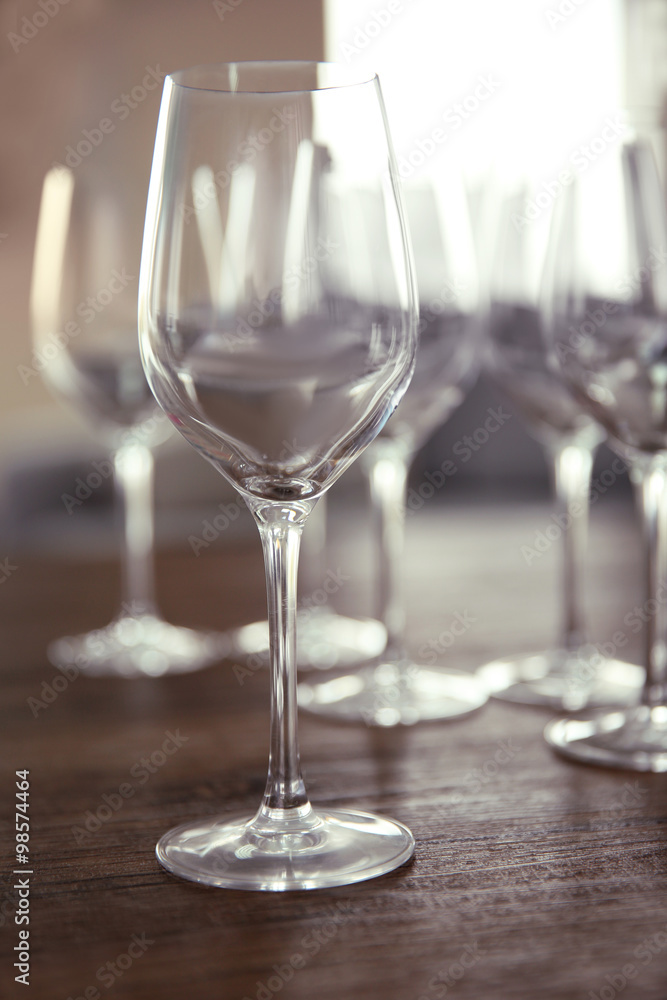 Empty wine glasses on wooden table against blurred background Empty wine glasses on wooden table against blurred background