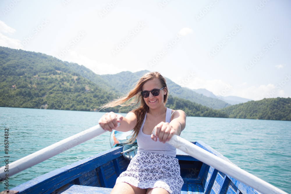 A young woman is rowing a boat on a summer day