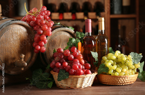 Grapes in bowls and barrel on wooden table