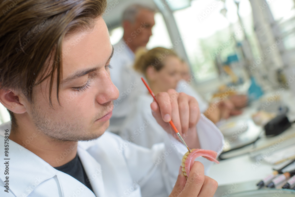 Male technician adding colour to dentures Male technician adding colour to dentures