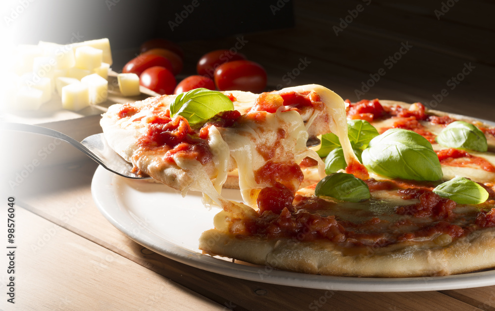 Pizza with tomatoes mozzarella and basil on the wooden table Pizza with tomatoes mozzarella and basil on the wooden table