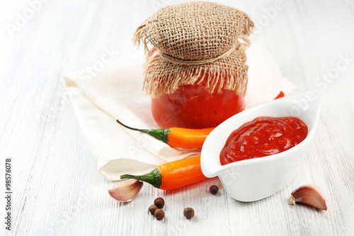 Homemade hot sauce and spices on light wooden background
