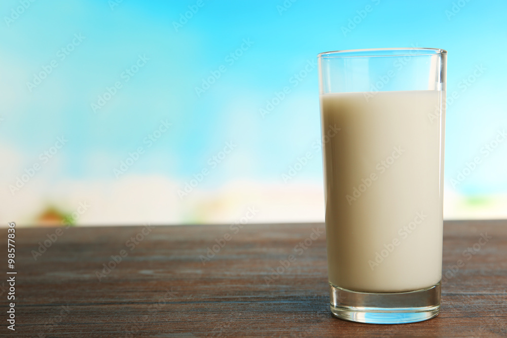 Glass of milk on table on blurred natural background Glass of milk on table on blurred natural background