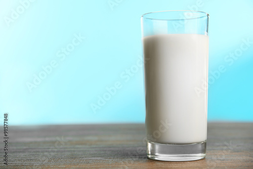Glass of milk on table on blue background