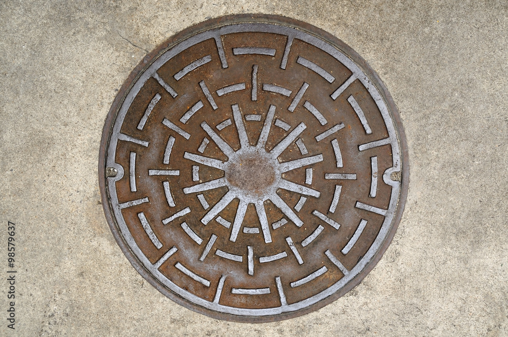 Manhole cover on street, top view.
