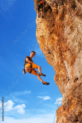 Rock climber hanging on belay rope againstthe mountains