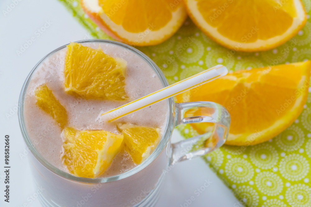 Healthy orange fruit smoothie in a glass with fresh orange slices in background, top view Healthy orange fruit smoothie in a glass with fresh orange slices in background, top view