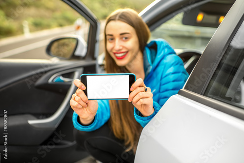 Woman showing phone sitting in the car