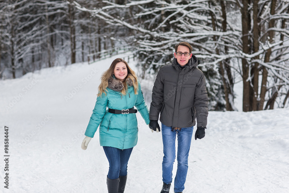 Young beautiful couple walking in winter forest