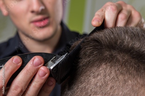 Hairdresser cutting clients hair with an electric hair clipper