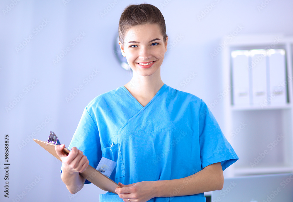 Smiling female doctor with a folder in uniform standing at hospital Smiling female doctor with a folder in uniform standing at hospital