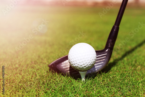 Golf club and ball on a green grass, close up