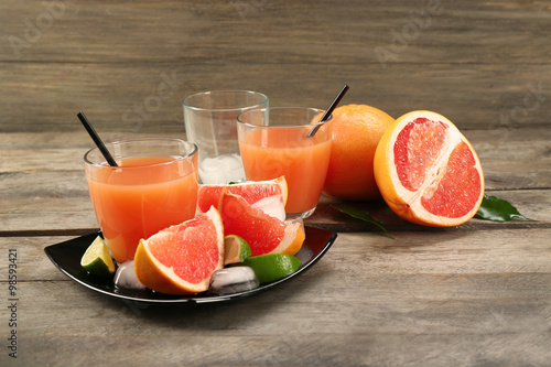Citrus juice and fresh fruits on black plate