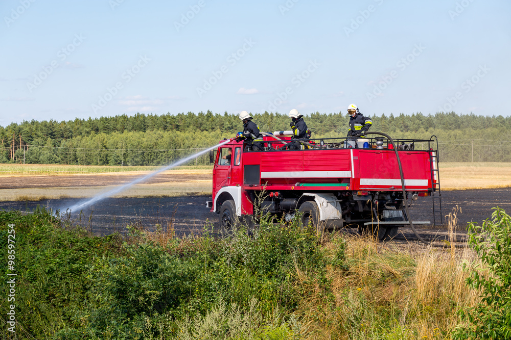 Firefighters truck working on the field on fire Firefighters truck working on the field on fire
