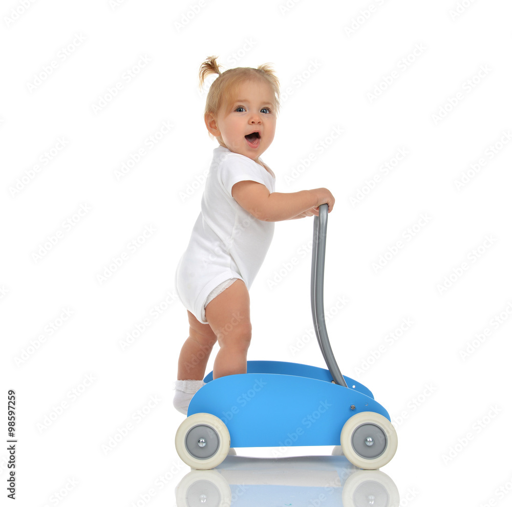 Cute smiling baby girl toddler with toy walker make first steps Cute smiling baby girl toddler with toy walker make first steps