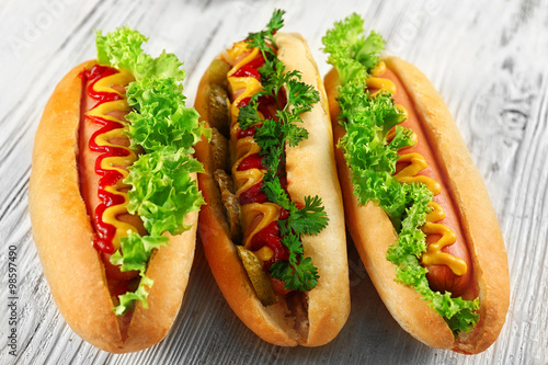 Delicious hot-dogs on white wooden background, close up