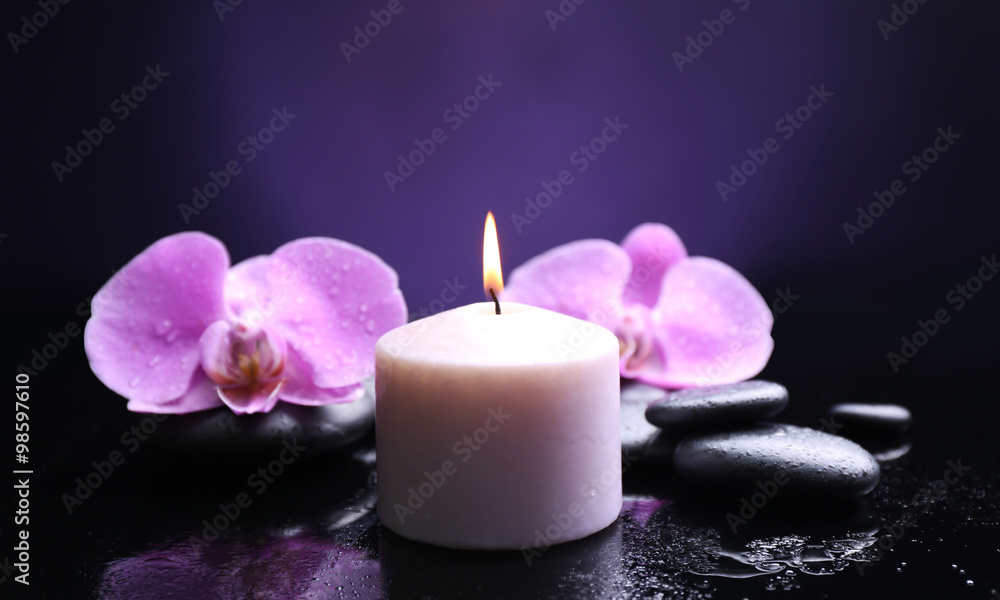 Composition of orchid, pebbles and candle on dark background