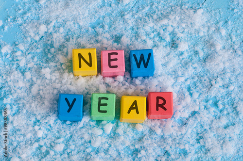 happy new year written with toy color cubes. on snow background photo