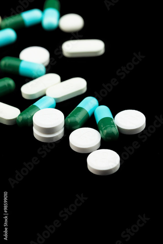 Pharmaceutical medicament, cure in container for health. Antibiotic, painkiller closeup. Medicine pills or capsules over black color background.