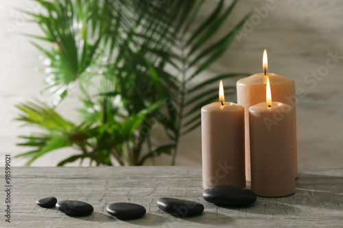 Spa composition of candles  stones and green leaves on light background