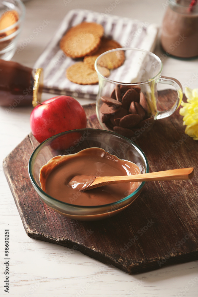 Melted chocolate in glass bowl, on wooden background Melted chocolate in glass bowl, on wooden background
