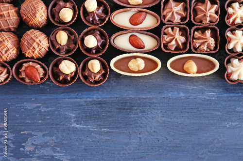 Delicious chocolate candies on blue wooden background