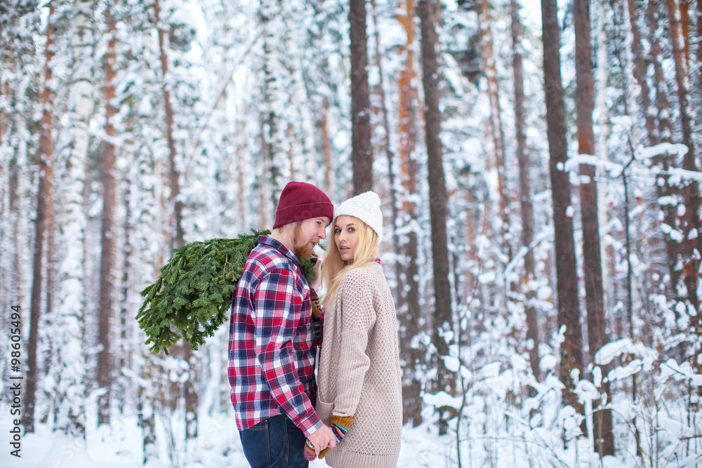 young couple in a plaid shirt with fir twigs walk in the winter woods