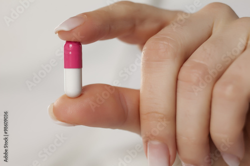 female hand holding a capsule with her fingers