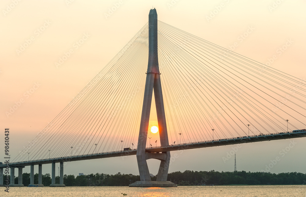 Fototapeta premium Can Tho, Vietnam - April 4th, 2015: close-up of cable stayed bridge at sunset with the sun in the abutment shown brilliant achievements of human development in the Mekong Delta in Can Tho, Vietnam