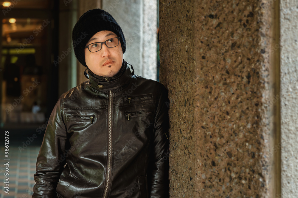 An Asian Man in a Brown Jacket Against the Wall An Asian Man in a Brown Jacket Against the Wall