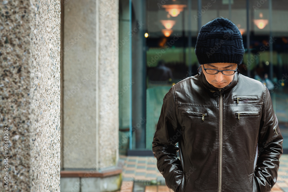 An Asian Man in a Brown Jacket is walks in a Street An Asian Man in a Brown Jacket is walks in a Street
