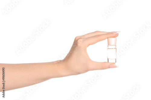 Perfume and body care theme: beautiful female hand holding a small transparent bottle of perfume on a white background isolated