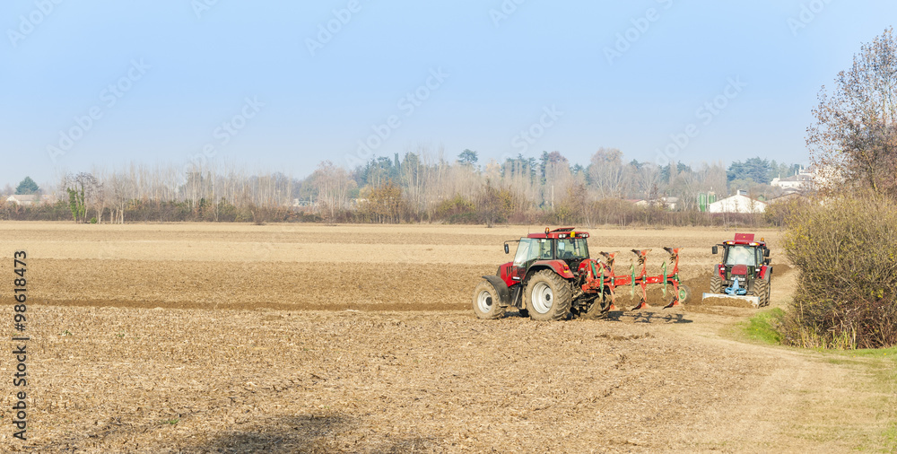 Obraz premium Red Tractor Plowing in Autumn.