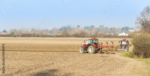 Red Tractor Plowing in Autumn.